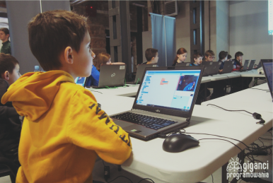 Zdjęcie przedstawia uczniów siedzących przed komputerami podczas warsztatów "Giganci Programowowania".